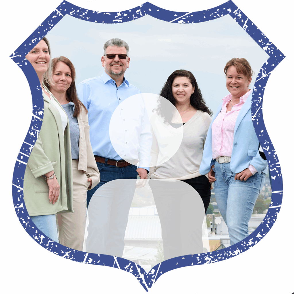 Gruppenbild von fünf Teammitgliedern, stehend im Freien vor städtischer Kulisse, alle lächeln freundlich.